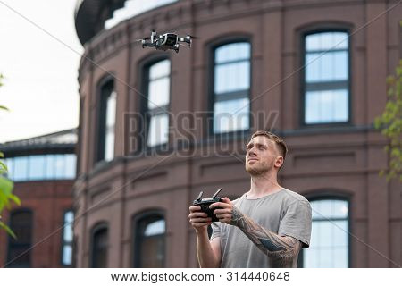 Young Handsome Man Launching Drone Quadcopter At Urban Background.
