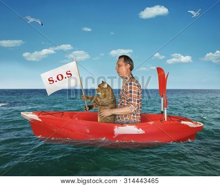 The Man With His Cat Are Drifting In A Red Kayak On The Sea After A Shipwreck. The Cat Holds A Sign 