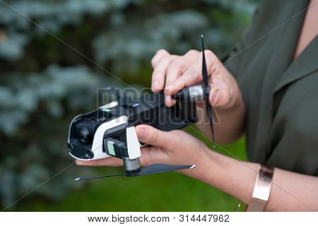 Close Up Of Woman Folding Drone Quadcopter At Park.