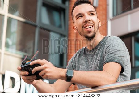 Young Handsome Man With Drone Quadcopter Joystick Controller At Urban Background.