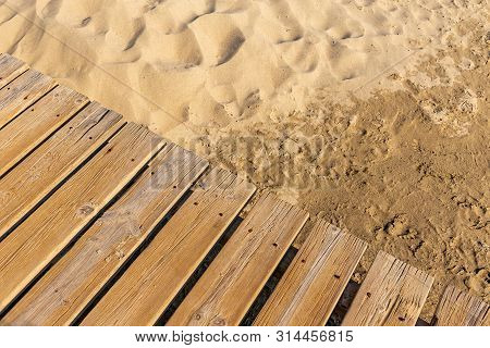Weathered Wooden Boardwalk On Sand. Aged Beach Brown Wooden Floor Over Summer Sand