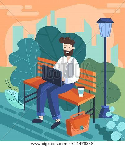 Businessman Enjoying A Break From The Office Working On A Laptop Computer On A Park Bench Outdoors, 