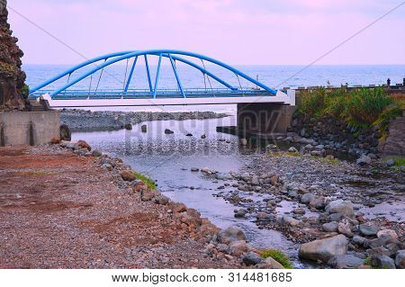 Evening Landscape. Sunset. A Small Mountain River Flows Into The Atlantic Ocean. Across The River Is