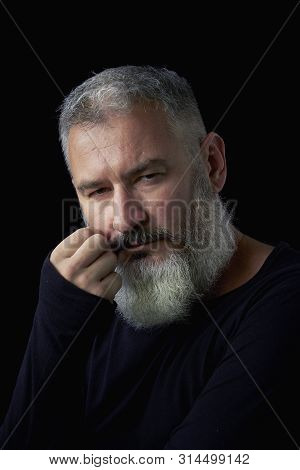 Portrait Of A Brutal Gray Haired Man With A Gray Lush Beard And Strict Face On A Black Background, S
