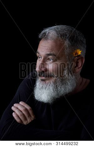 Portrait Of A Brutal Gray-haired Man With A Beard With A Joking Expression On His Face And A Yellow