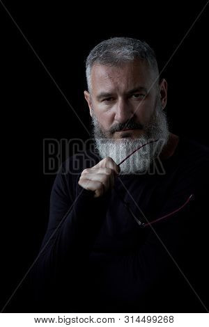 Artistic Portrait Of A Brutal Gray Haired Man With A Beard And Glasses On A Black Background, Select