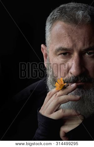 Portrait Of A Brutal Gray Haired Man With A Beard With A Sly Expression On His Face And A Yellow Flo