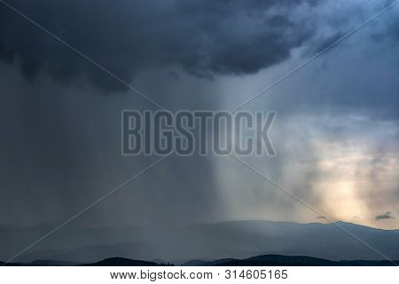 The Rain From The Clouds Gradually Covers The Mountains.