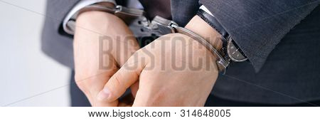 Close-up Of Handcuffed Male Arms In Bracelets. Criminal Wearing Expensive Classy Suit. Arrested Brib