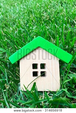 Miniature Wooden House On Grass. Real Estate Concept. Eco-friendly And Energy Efficient House. Buyin