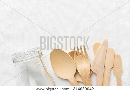 Glass Bottle Wooden Cutlery Spoon Fork Knife On White Cotton Textile Background. Zero Waste Reusable