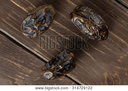 Group Of Three Whole Dried Brown Date Medjool Flatlay On Brown Wood