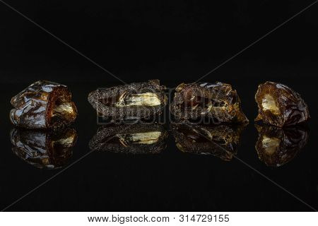 Group Of Four Halves Of Dried Brown Date Medjool Isolated On Black Glass