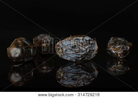 Group Of Four Whole Dried Brown Date Medjool Isolated On Black Glass