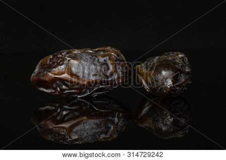 Group Of Two Whole Dried Brown Date Medjool Isolated On Black Glass