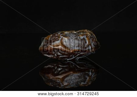 One Whole Dried Brown Date Medjool Isolated On Black Glass
