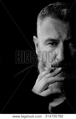 Black And White Portrait Of A Brutal Gray Haired Man With A Beard With A Yellow Flower In His Hands