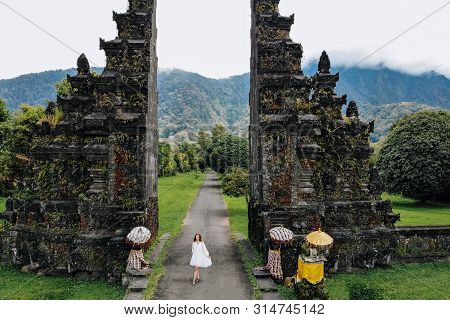 Tourist Woman Walking Through Traditional Balinese Hindu Gate Candi Bentar Close To Bedugul, Bratan 