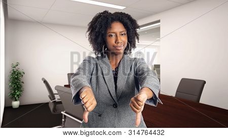 Black African American Businesswoman In An Office With Thumbs Down.  She Is An Owner Or An Executive