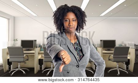 Black African American Businesswoman In An Office With Thumbs Down.  She Is An Owner Or An Executive