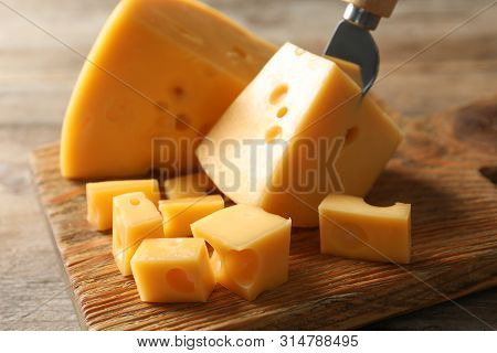 Serving Board With Delicious Cheese On Wooden Table, Closeup