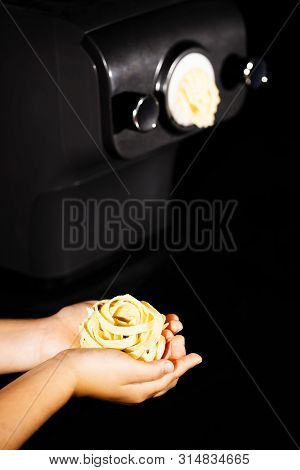 Hands Of A Little Girl Holding E Fresh Home-maded Tagliatelle Pasta. Pastamaker In Background
