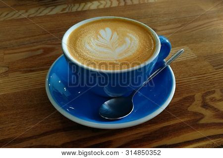 A Blue Cup Of Coffee With A Spoon Is On The Table