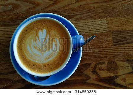 A Blue Cup Of Coffee With A Spoon Is On The Table