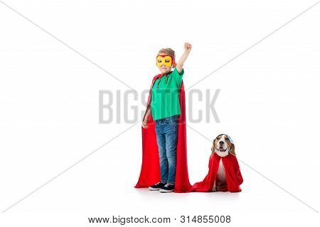 Full Length View Of Preschooler Child With Fist Up And Beagle Dog In Masks And Red Hero Cloacks Isol