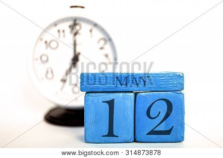 May 12th. Day 12 Of Month, Handmade Wood Calendar And Alarm Clock On Blue Color. Spring Month, Day O