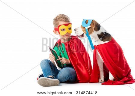 Preschooler Child And Beagle Dog In Masks And Red Hero Cloacks Sitting With Digital Tablet On White