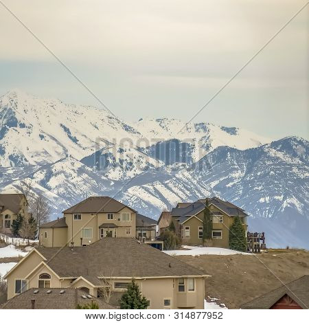 Square Winter View Of A Neighborhood On A Hill Against Mountain And An Overcast Sky