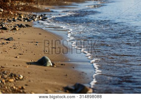 Sea Waves Of The Blue Sea With Foam Roll Ashore The Golden Shore. Close-up