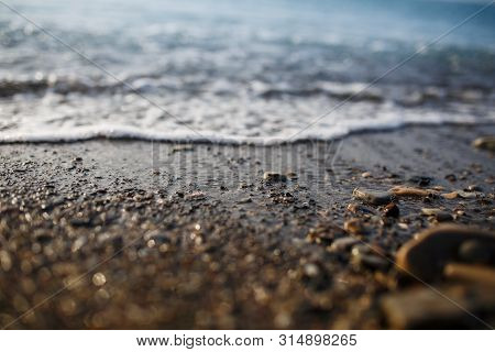 Sea Waves Of The Blue Sea With Foam Roll Ashore The Golden Shore. Close-up
