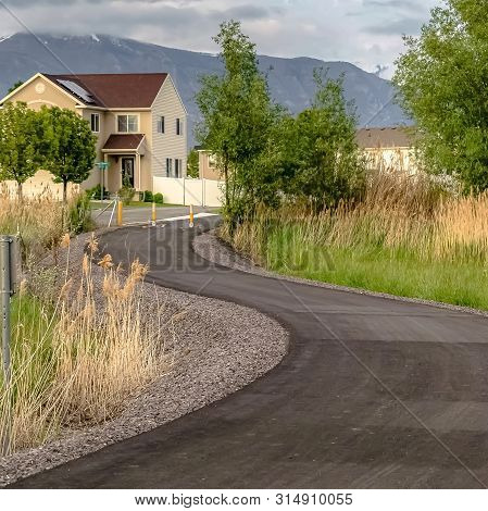 Square Paved Road With Yellow Traffic Delineator Posts Winding Through A Grassy Field