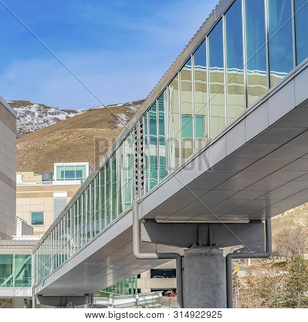 Frame Skybridge Connected To A Modern Building With Mountain And Blue Sky Background