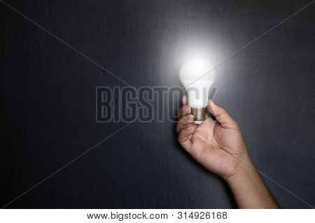 Manhand With Light Bulbs And Abstract Ideas On The Background Of A Dark Wall