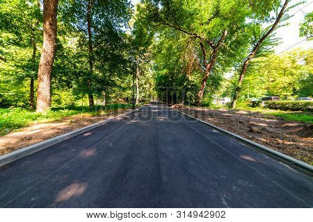 Asphalt Walking Path Through The City Park.