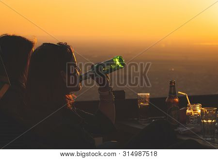 Beautiful Woman Drinking Beer In Sunset. Woman Drinking Beer In Summertime On Bar Terrace. Woman Dri