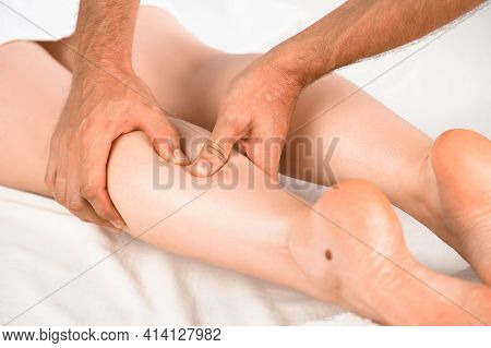 The Masseur Massages The Calf Muscle Of The Girl Lying On The Massage Table. Very Close-up, Soft Lig