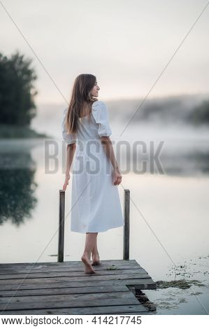 Tender Romanitc Sentimental Female Lady In The Morning On A Wooden Pier Near The Misty River In A Wh