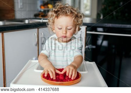 Healthy Eating. Cute Caucasian Baby Boy Eating Ripe Red Fruits At Home. Funny Child Kid Sitting High