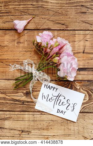 Happy Mother's Day Card And Pink Flowers On A Wooden Table  Top View