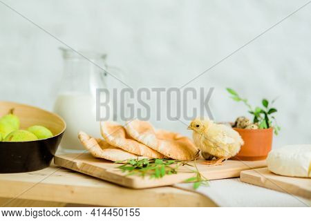 Yellow Little Chicken On The Table With Easter Deoration, Bread, Cheese And Greenery. Horisontal Pic