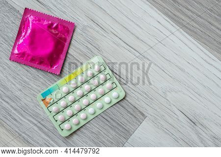 Contraceptive Pills And Condoms On Wooden Floor. Concept Of Birth Control Objects Or Device Used To 