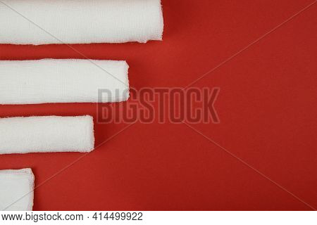 On A Red Background, Three Bandages And Medical Wipes. Top-down Layout
