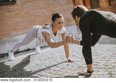 Young Couple Doung One Arm Pushup Exercise In The Urban Environment