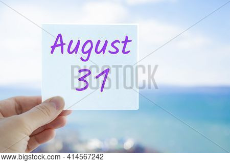 August 31st. Hand Holding Sticker With Text August 15 On The Blurred Background Of The Sea And Sky. 