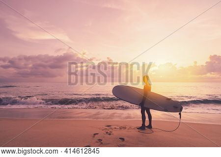 Man Hold Surfboard Standing At Tropical Sunset Beach Background. Summer Vacation And Sport Adventrue