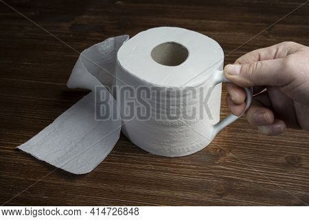 A Roll Of Toilet Paper Used As A Cup On A Wooden Table